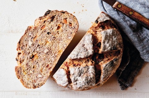 Loaf of No-Knead Harvest Bread, this fruit bread has been cut in half showing that itis filled with dried fruits and nuts. - select to zoom