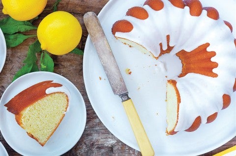 An overhead photo of Glazed Lemon Bundt Cake. One large slice has been removed and laid on its side on a plate next to the cake showing off the tender interior crumb. - select to zoom