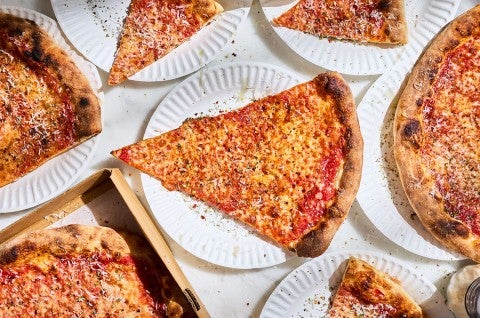 Slices of New York-Style Pizza paper plates arranged on a table seen from above. - select to zoom