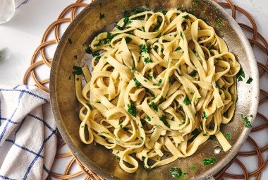 A bowl of gluten free pasta dressed with parmesan and parsley.